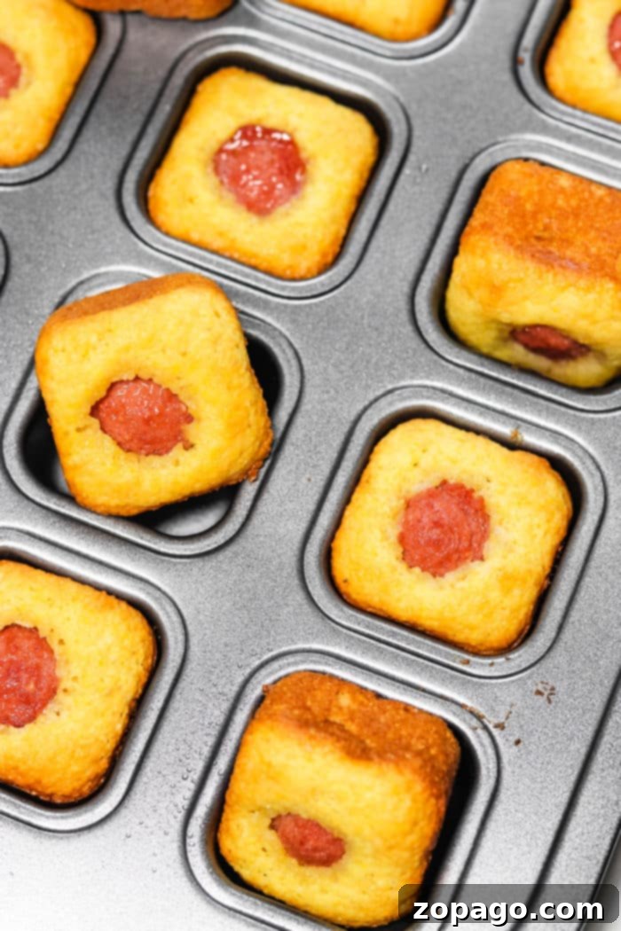 Golden Corn Dog Nuggets 2 Golden brown Jiffy Corn Dog Bites nestled in a mini muffin tin, ready to be served.