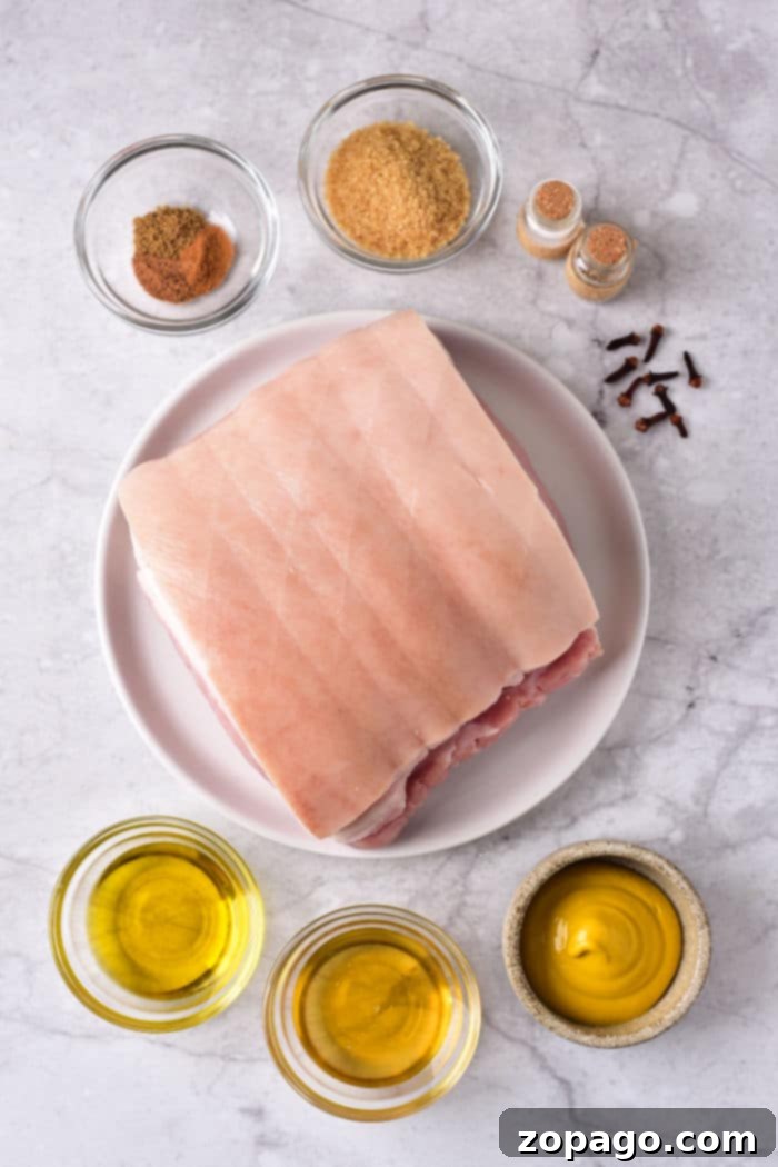 Easy Oven-Roasted Pork Perfection 3 A slab of pork roast on a plate sits elegantly on a marble surface, surrounded by bowls of spices, oil, and mustard, hinting at the perfect preparation for those wondering how long to cook a pork roast in the oven at 375.