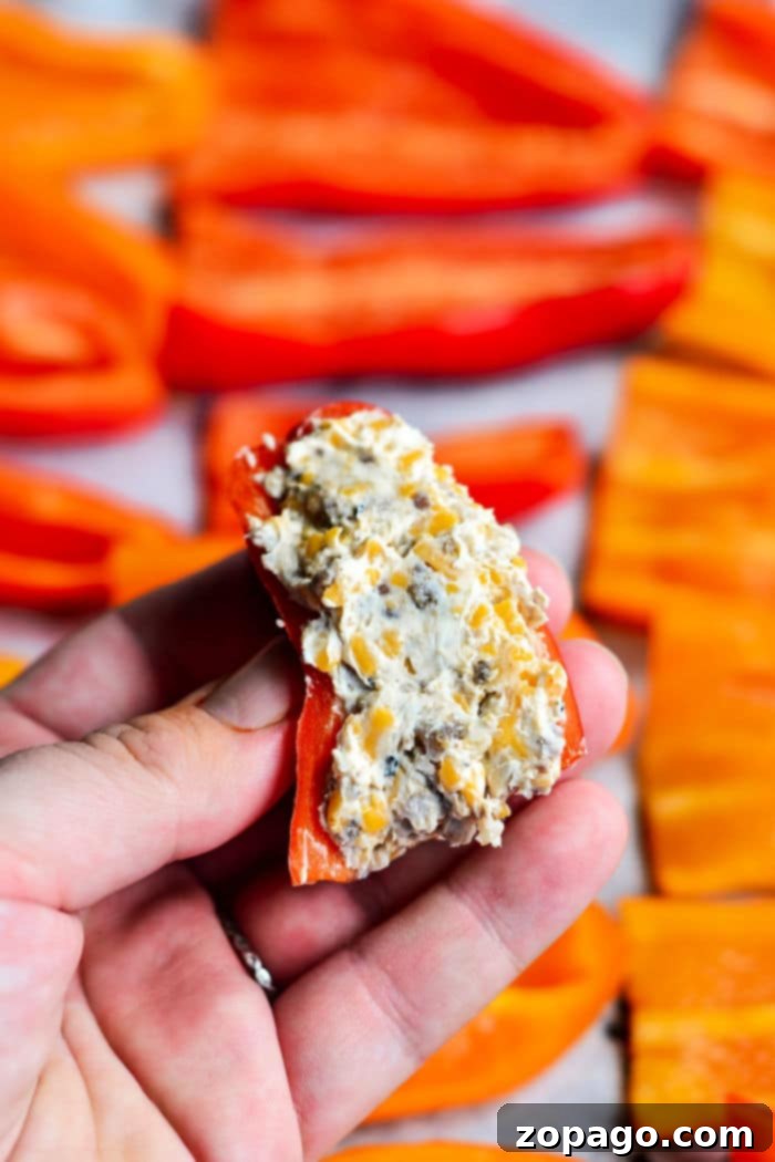 Mini Stuffed Sweet Peppers 4 A hand holds a freshly prepared cream cheese stuffed mini sweet pepper, showcasing the creamy filling and vibrant pepper color.