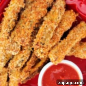 Plate of crispy breaded eggplant fries with a side of red dipping sauce.