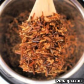 Perfect Instant Pot Black Rice 5 A wooden spoon lifts cooked wild rice from a Black Rice Instant Pot.