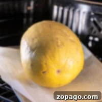 Baking Whole Spaghetti Squash 6 A whole yellow spaghetti squash is roasting to perfection on parchment paper, nestled in the warmth of the oven.