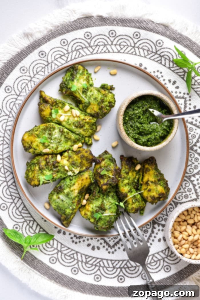 Ultimate Air Fryer Pesto Chicken 7 Pesto Chicken - a close-up of tender pesto-coated chicken, garnished with fresh basil leaves.