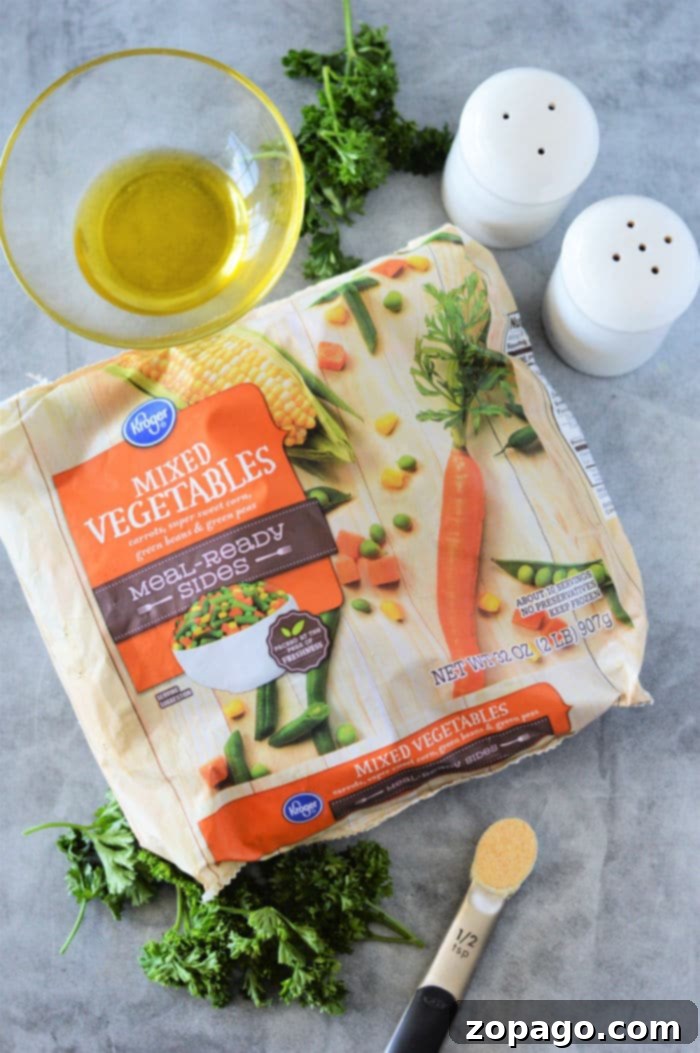 Crispy Roasted Frozen Vegetables 3 A package of mixed vegetables, ideal for roasting frozen vegetables, features a carrot and corn design on a gray surface. Nearby are a bowl of oil, parsley sprigs, a half teaspoon of garlic powder, a spoon, and salt and pepper shakers.