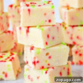 A stack of festive white fudge squares made with cookie mix and condensed milk, adorned with red and green sprinkles on a marble surface.