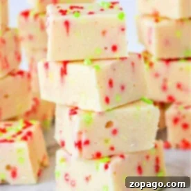 A stack of festive white fudge squares made with cookie mix and condensed milk, adorned with red and green sprinkles on a marble surface.