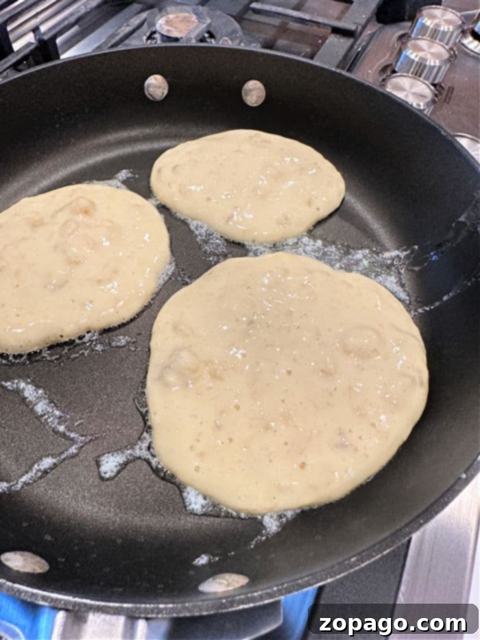 Banana Chocolate Chip Pancake Bliss 4 A close-up of golden-brown banana nut pancakes on a griddle, ready to be flipped.