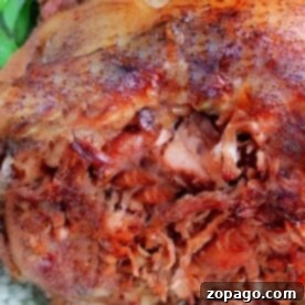 Close-up of roasted pulled pork shank with crispy edges on a plate, garnished with green herbs, reminiscent of a savory pork shank feast.