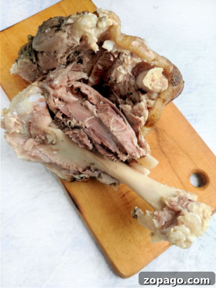 Crispy Pork Knuckle 7 A sumptuous pork shank, bone and tender meat on display, rests elegantly on a wooden board.