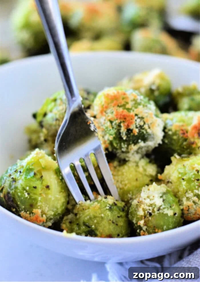 Perfect Microwave Brussels Sprouts 2 A bowl of microwaved Brussels sprouts with Parmesan cheese, how to microwave Brussels sprouts to perfection, all flawlessly pierced by a fork.