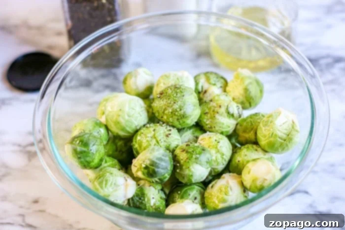 Perfect Microwave Brussels Sprouts 3 A glass bowl filled with Brussels sprouts sits elegantly on a marble countertop.