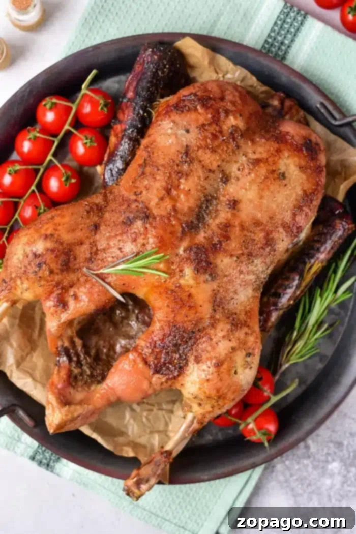 From Freezer to Fork: Cooking Delicious Duck 2 Roasted whole duck, beginning its journey as a frozen delight, sits on a tray with herbs and charred sausages. Cherry tomatoes on the vine garnish the side. The tray rests elegantly on a green cloth against a neutral backdrop.