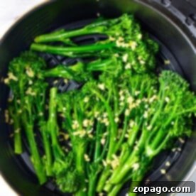 Air Fryer Broccolini: Fresh broccolini with chopped garlic sits in the air fryer basket, ready to be cooked to perfection.