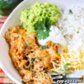 A bowl of Chicken Poblano with shredded chicken, melted cheese, guacamole, sour cream, and rice, garnished with cilantro.
