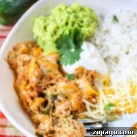 Savory Poblano Chicken 5 A bowl of Chicken Poblano with shredded chicken, melted cheese, guacamole, sour cream, and rice, garnished with cilantro.