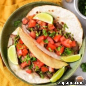 Lengua Tacos 6 A plate of flavorful cow tongue tacos topped with diced tomatoes, fresh cilantro, and lime wedges sits on a yellow cloth. Nearby, bowls of zesty salsa and creamy guacamole await to complement the vibrant dish.