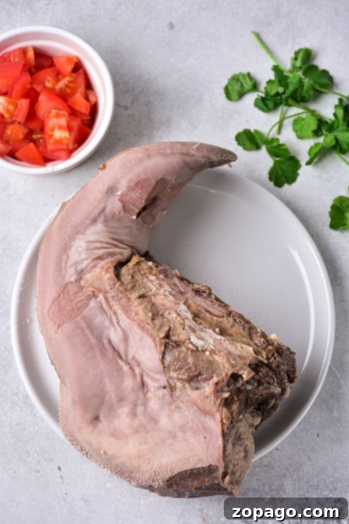 Cooking Tender Beef Tongue 4 A large pot of simmering liquid with a whole cow tongue and vegetables, illustrating the stovetop cooking method.
