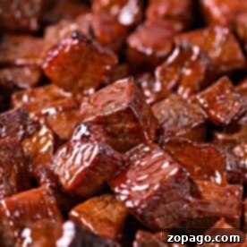 A tray filled with glazed, cubed pieces of barbecue chuck roast burnt ends, all glistening with sauce.