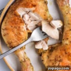 Baked chicken leg quarters rest on a plate as a fork gracefully slices through the tender meat.