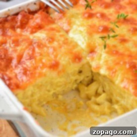 A baked mac and cheese with heavy cream casserole boasts a golden, bubbly top and a slice removed, revealing creamy pasta inside.