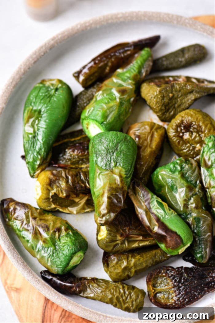 Oven-Roasted Jalapeños 2 Vibrantly green roasted jalapeno peppers, smoky and slightly charred, arranged beautifully on a rustic ceramic plate.
