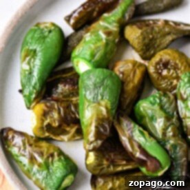 Roasted jalapeno peppers in oven, vibrant and smoky, rest elegantly on a ceramic plate.