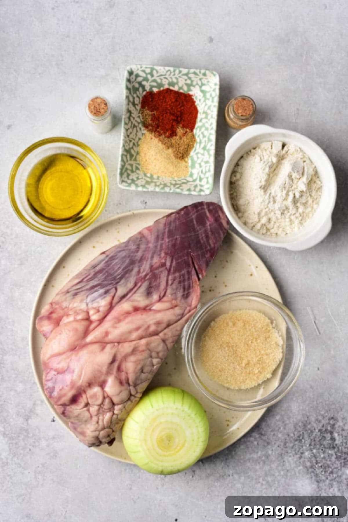 Mastering Beef Heart Cooking 3 How to Cook Beef Heart: Raw beef heart, onion, flour, oil, brown sugar, and spices arranged on a light gray countertop.