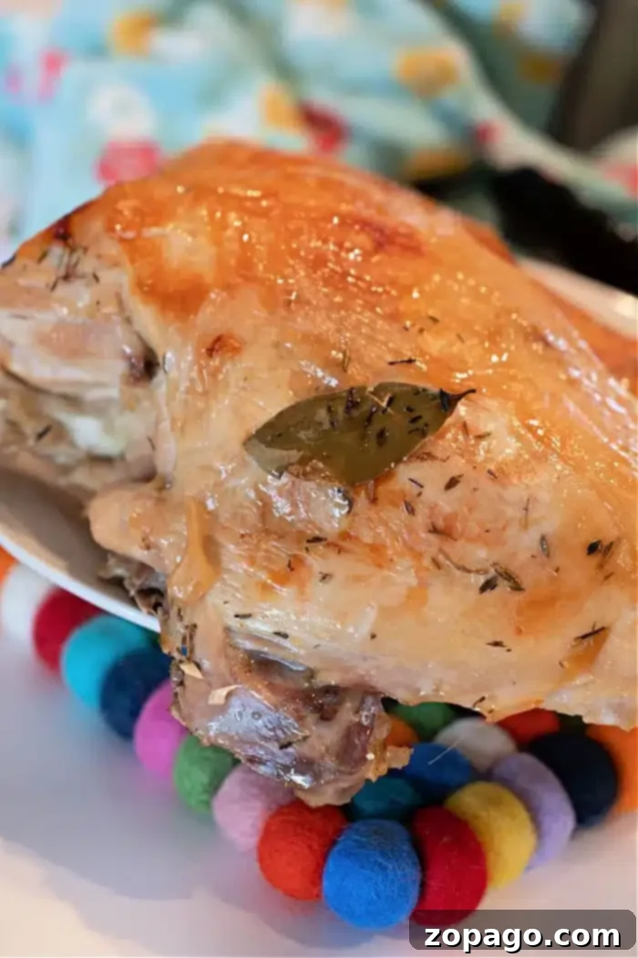Perfectly Roasted Butterball Turkey Breast 2 A beautifully roasted turkey breast with golden-brown, crispy skin and fresh herbs, including a bay leaf, resting on a rustic trivet. The image evokes the perfect result of cooking a Butterball turkey breast in the oven.