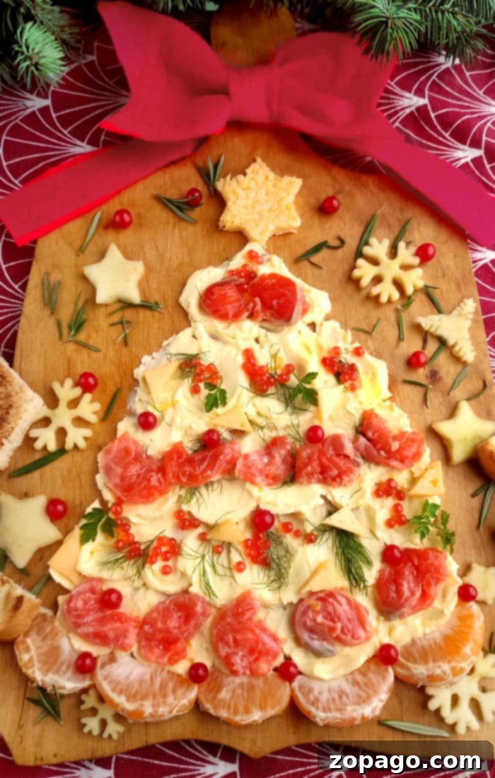 A festive Christmas tree butter board adorned with vibrant pomegranate seeds, fresh herbs, and a star-shaped cheese topper, ready for holiday entertaining.