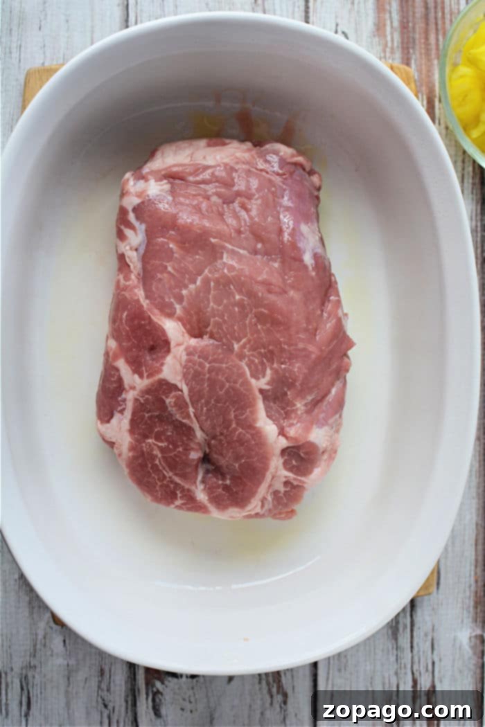 Slow-Cooked Mississippi Pork 3 A large, boneless pork roast resting in a baking dish, perfectly positioned for its slow bake in the oven.
