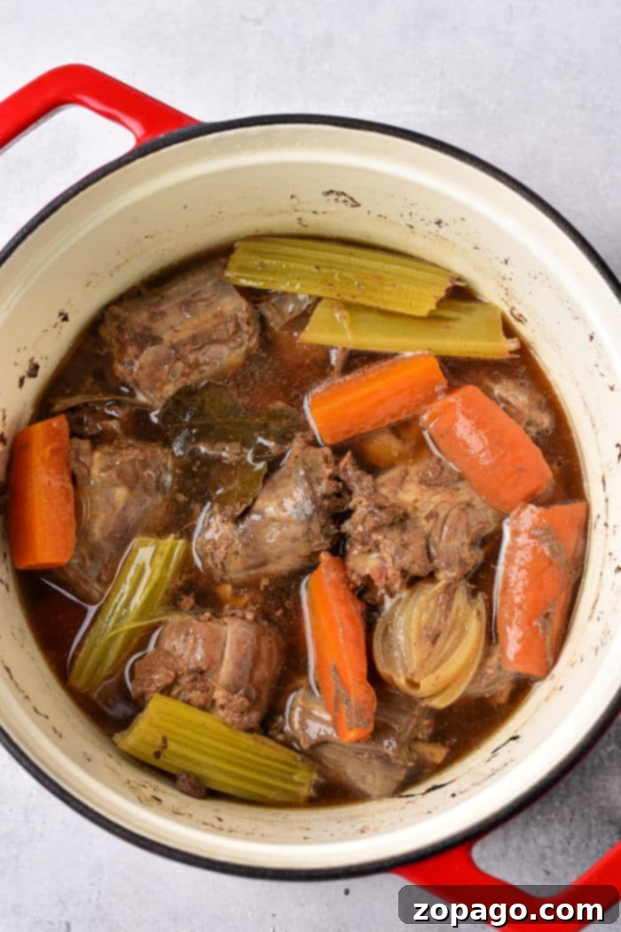 Slow-Simmered Turkey Neck Gravy 3 A pot of braised turkey necks, carrots, celery, and onion simmering gently, creating a rich base for gravy.