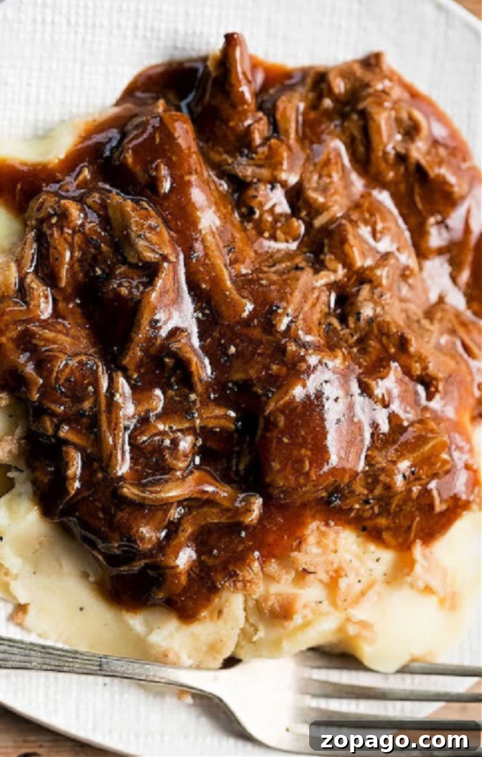Tender Boiled Turkey Necks 7 Mashed potatoes topped with tender turkey neck meat and rich gravy, served on a white plate with a fork
