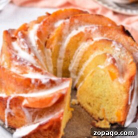 A sliced Peach Cobbler Pound Cake with icing drizzled on top, displayed on a light surface.