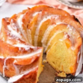 Golden Peach Cobbler Pound 5 A sliced Peach Cobbler Pound Cake with icing drizzled on top, displayed on a light surface.