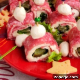 Pickle Roll Ups: Salami rolls with mozzarella and pickles, garnished with lettuce, on a red plate adorned with cheese stars.