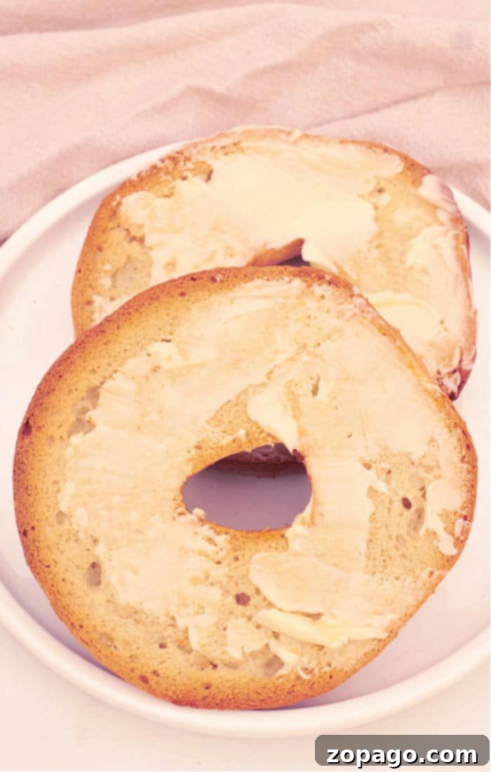 Mastering Oven-Toasted Bagels 5 Two perfectly buttered bagel halves rest on a white plate, showcasing the delicious result of oven-toasting, ready for your favorite toppings.