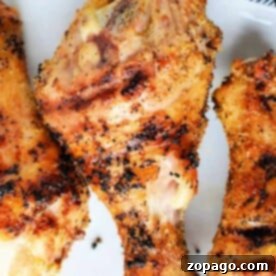 Smoky Grilled Chicken Drumsticks 5 Close-up of grilled, seasoned chicken drumsticks on a white plate.