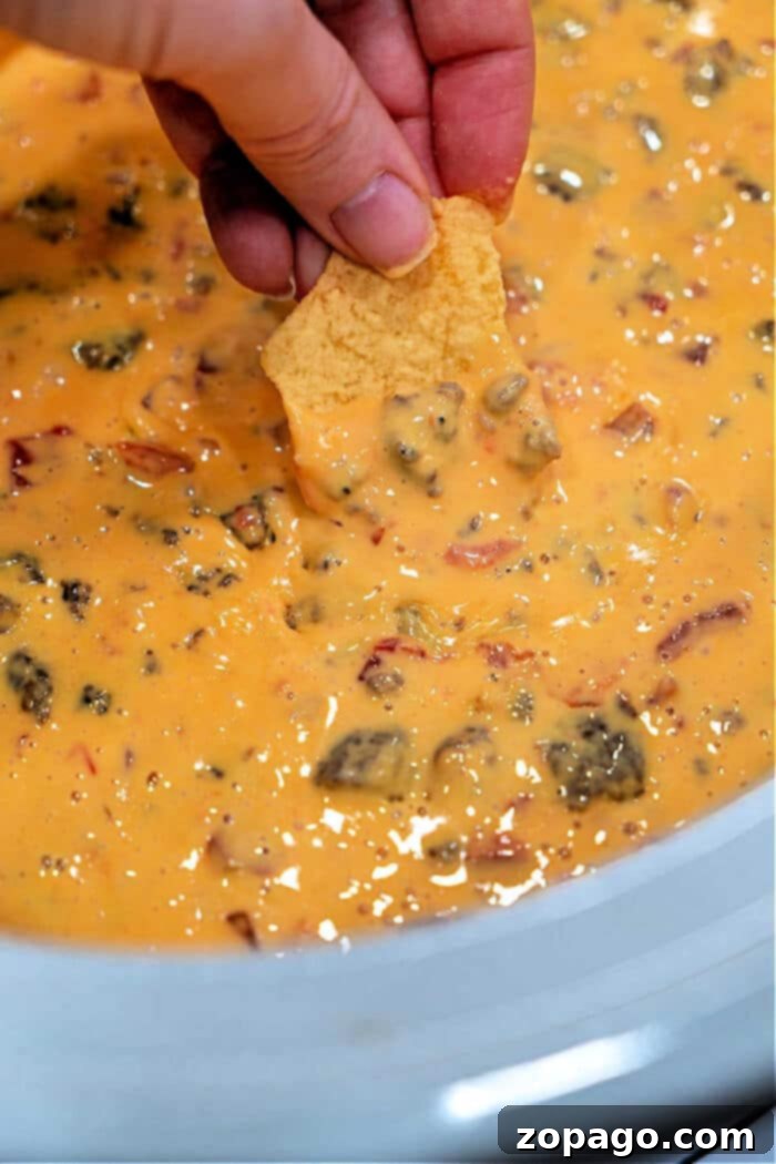 Slow Cooker Velveeta Sausage Dip with rotel, showing a generous amount of creamy dip with visible chunks of sausage and tomatoes.
