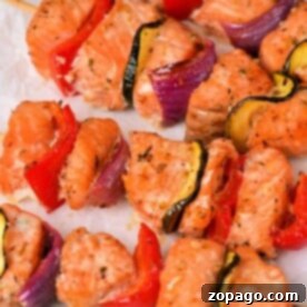 Grilled Salmon Kabobs with zucchini, red pepper, and red onion on parchment paper.