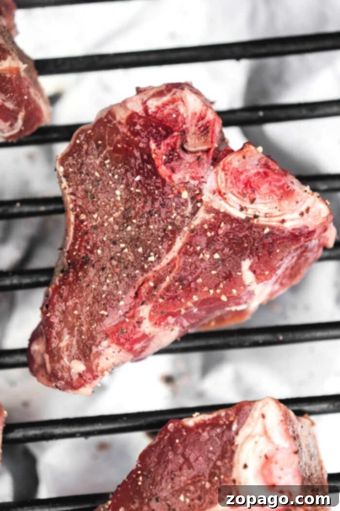 Perfectly Seared Lamb Loin Chops 5 A raw piece of seasoned lamb loin chop sits on a grill.