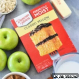 Apple Cobbler with Cake Mix: A delightful spread on the countertop featuring cake mix, green apples, oats, butter, milk, brown sugar, and a hint of cinnamon.