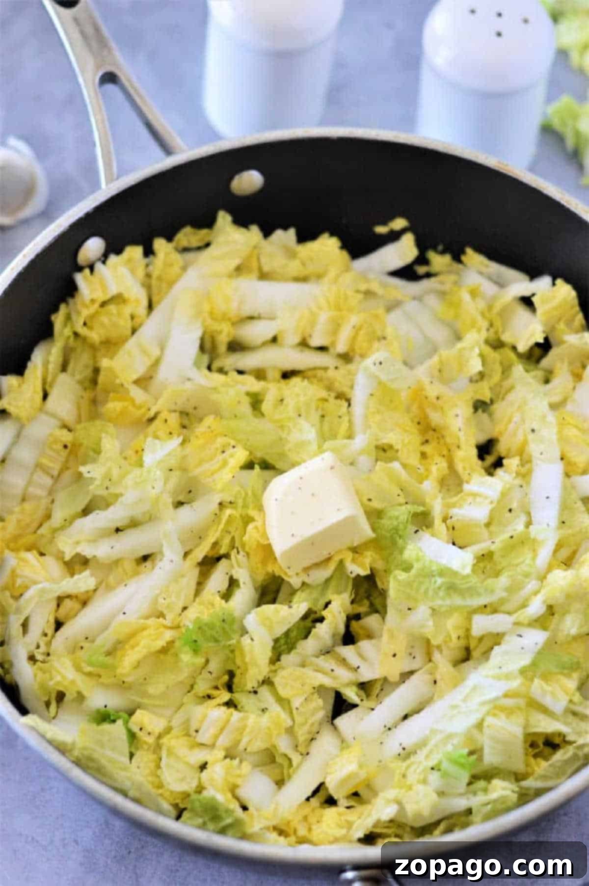 Easy Napa Cabbage Recipes 5 Chopped Napa cabbage with a pat of butter and black pepper in a skillet, ready to be cooked—an easy and delicious Napa cabbage recipe.