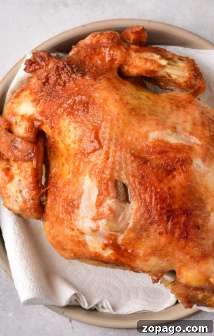 Crispy Whole Fried Chicken 6 A roasted whole chicken with crispy, golden-brown skin rests on a paper towel-lined plate, echoing the mouthwatering allure of a whole fried chicken.