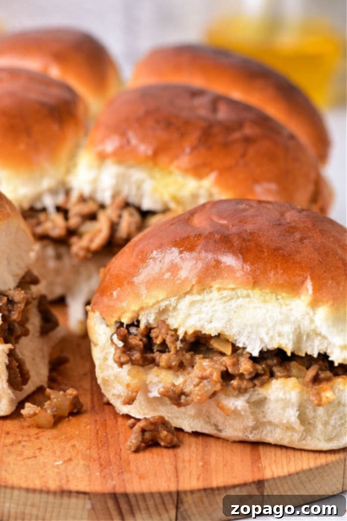 Saucy Mini Sloppy Joes 11 Sloppy Joe Sliders ready to be served, showing off their hearty filling and soft buns on a rustic wooden board.