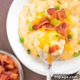 A bowl of Hashbrown Soup on Stove topped with cheese, bacon, and green onions sits invitingly beside a steaming pot of frozen Hashbrown Soup warming on the stove.