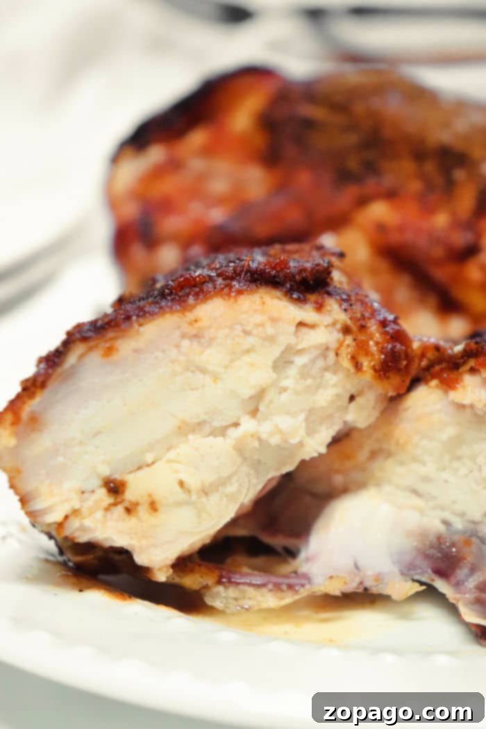 Close-up of three whole, juicy Traeger smoked chicken breasts, perfectly cooked with a smoky exterior, ready for serving.