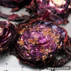 Roasted red cabbage slices lie on a baking sheet, perfectly seasoned with a medley of spices.