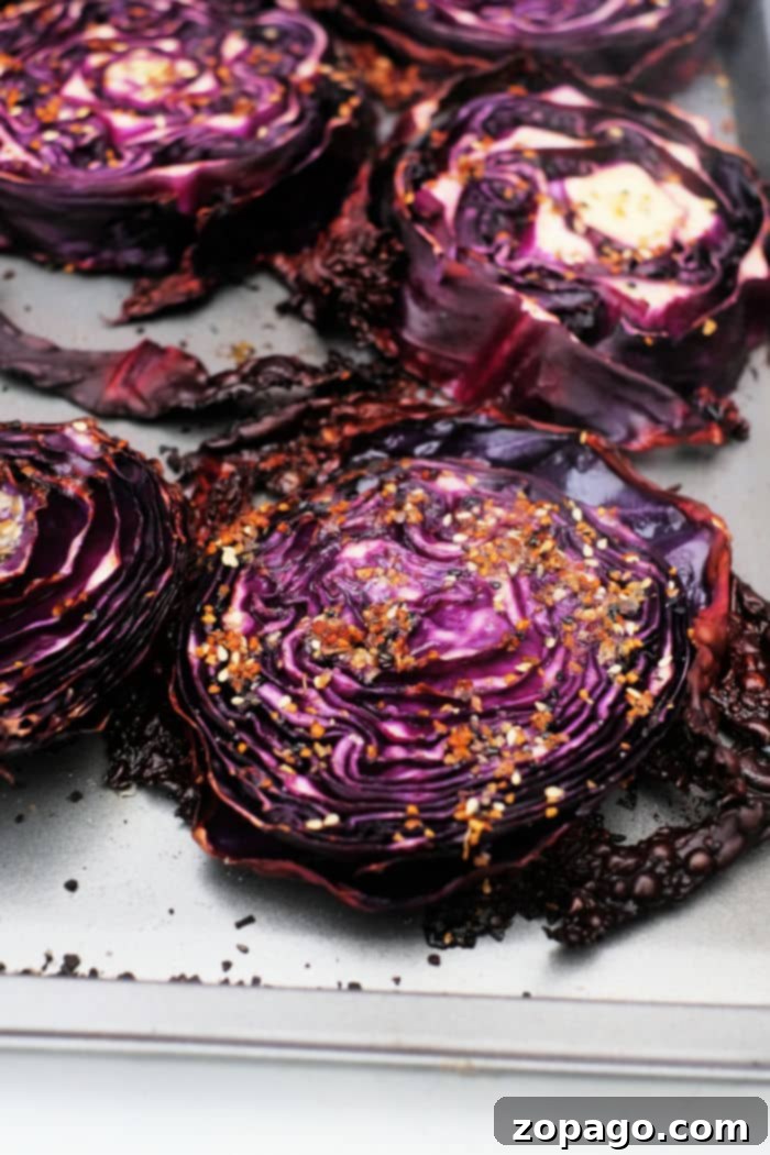 Caramelized Roasted Red Cabbage 7 Roasted Red Cabbage steaks on a baking sheet, glistening with butter and seasonings.