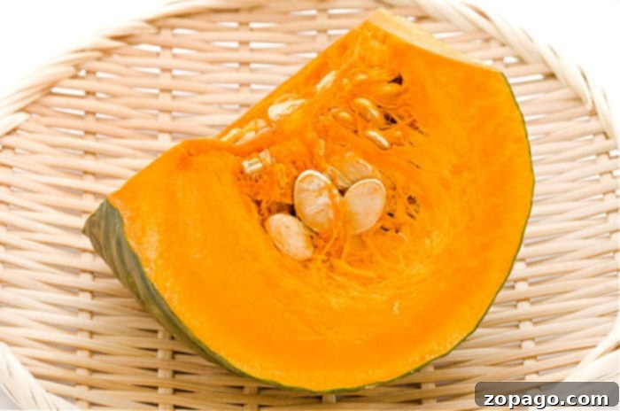 Velvety Kabocha Squash Soup 3 A slice of kabocha squash with seeds on a bamboo plate, highlighting its vibrant orange flesh.