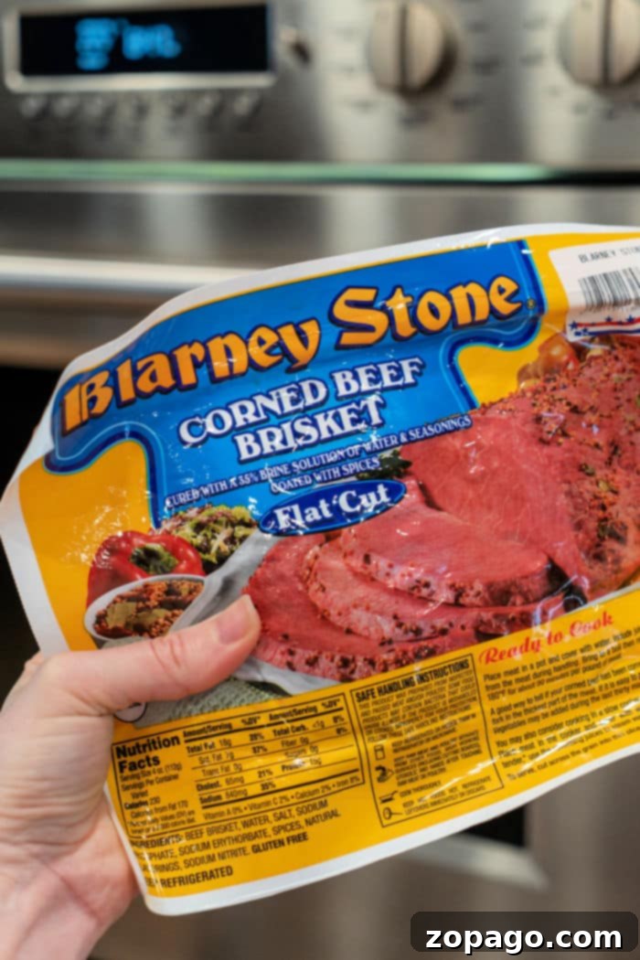 Perfectly Tender Oven Corned Beef 3 A whole corned beef brisket in a roasting pan, ready for the oven, surrounded by halved potatoes and immersed in a rich cooking liquid.